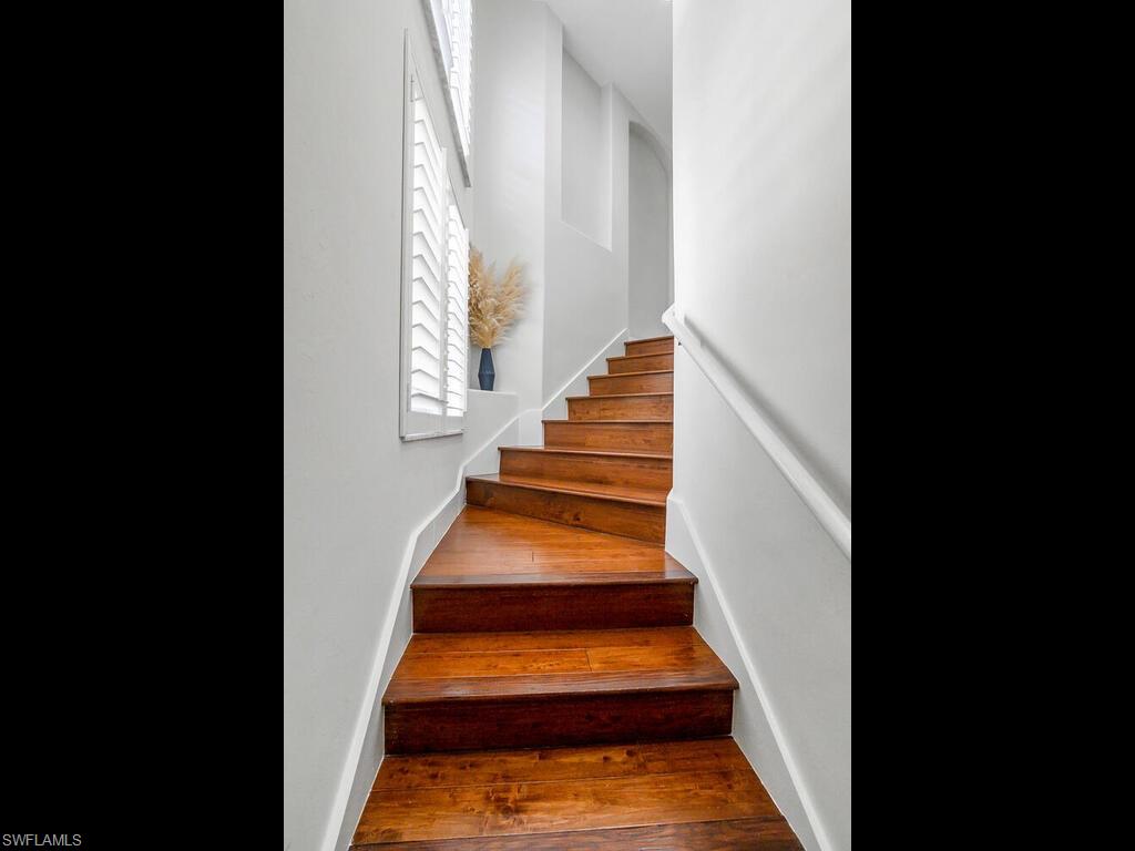 816 Carrick Bend Circle, Unit 202 Naples, FL 34110 - Photo 10 of 50 Staircase featuring hardwood / wood-style floors and baseboards