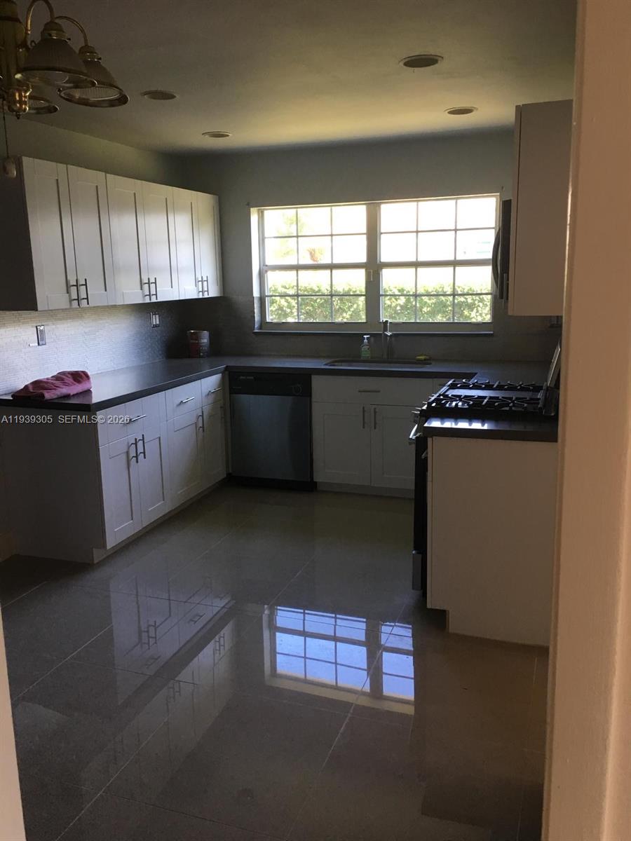 8111 Southwest 129th Avenue Miami, FL 33183 - Photo 4 of 20 a kitchen with granite countertop a stove a sink and a microwave