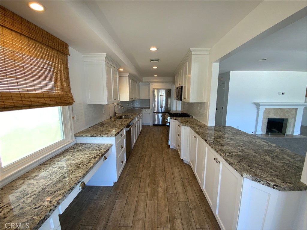 2137 Channel Road Newport Beach, CA 92661 - Photo 6 of 21 a large kitchen with stainless steel appliances granite countertop wooden floor a large counter top and a stove