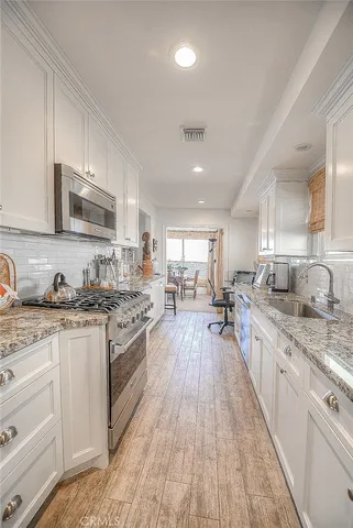 a large kitchen with stainless steel appliances granite countertop a lot of counter space and wooden floors