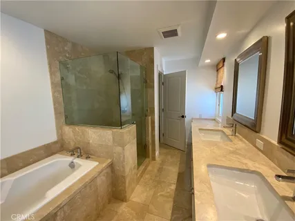 a spacious bathroom with a tub sink and mirror