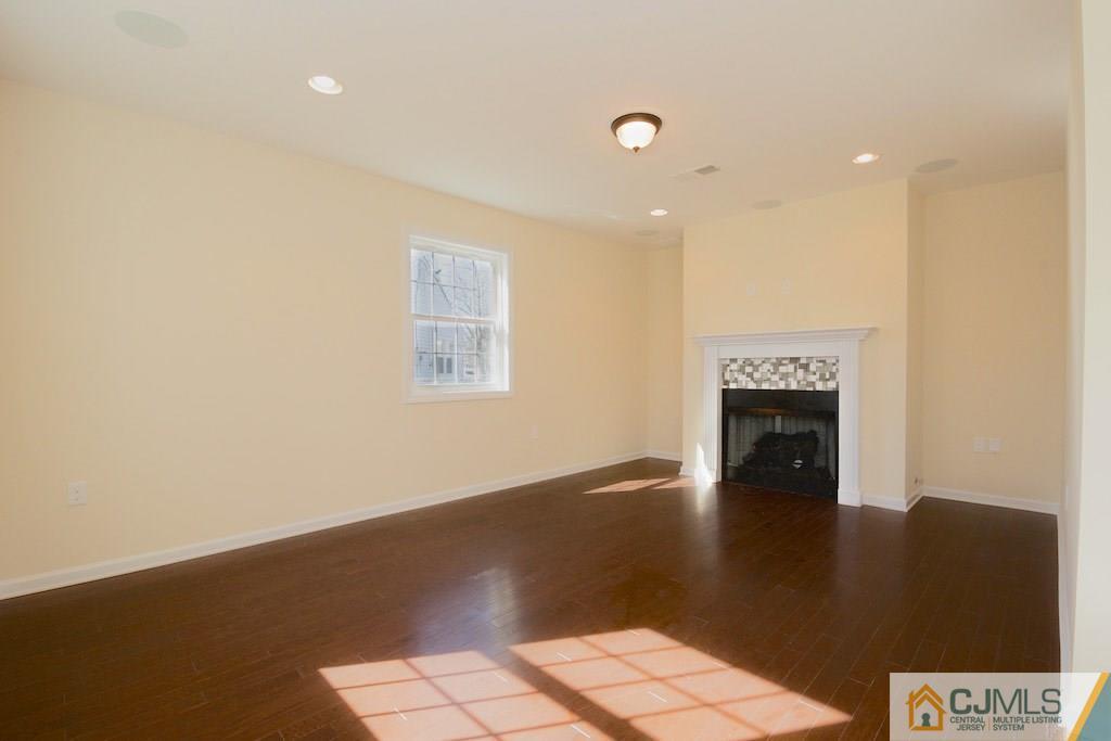 60 Ashley Road Edison, NJ 08817 - Photo 7 of 9 an empty room with wooden floor fireplace and windows