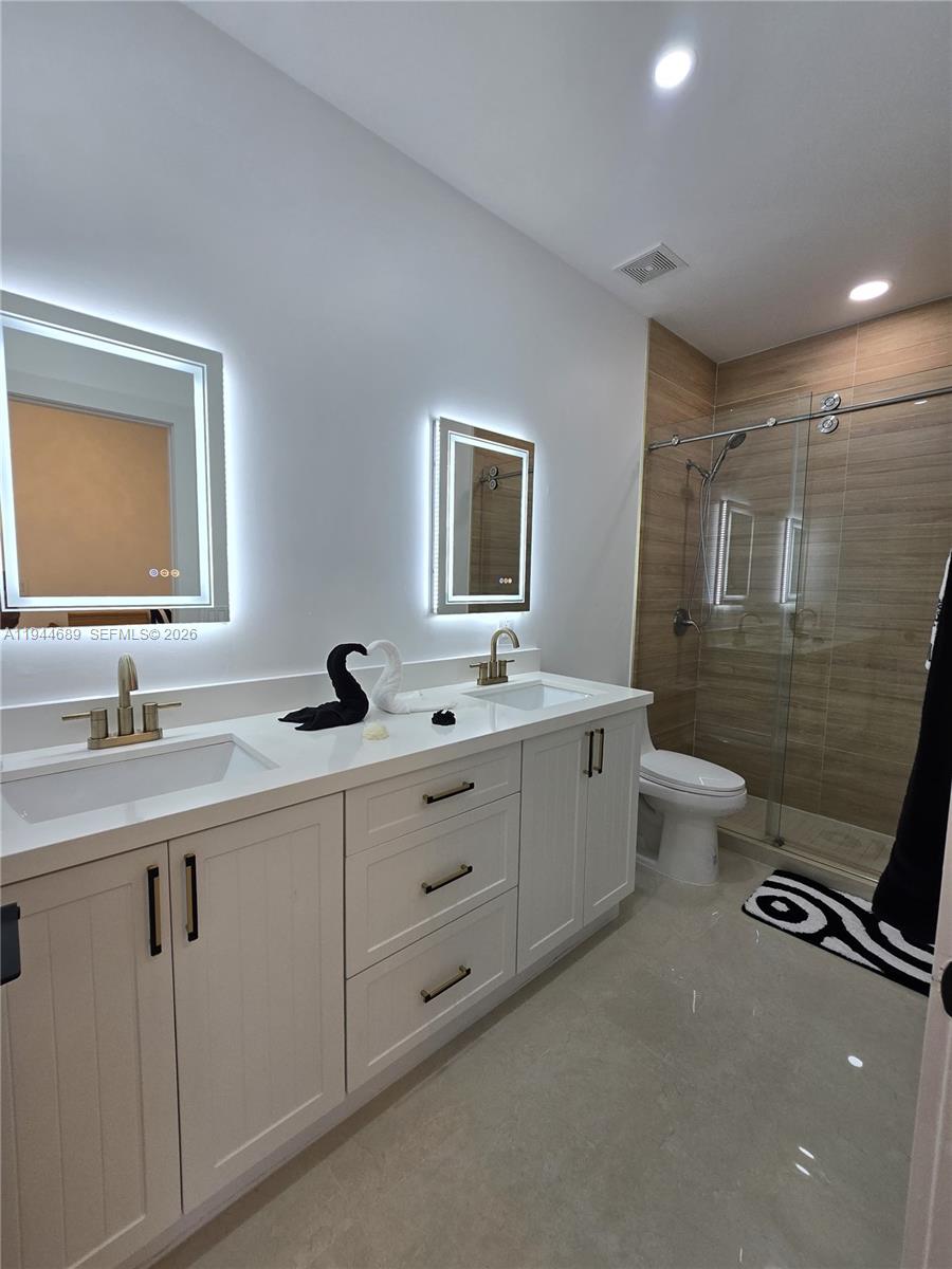 1680 Southwest 154th Path Miami, FL 33185 - Photo 66 of 100 a bathroom with a double vanity sink toilet mirror and bathtub
