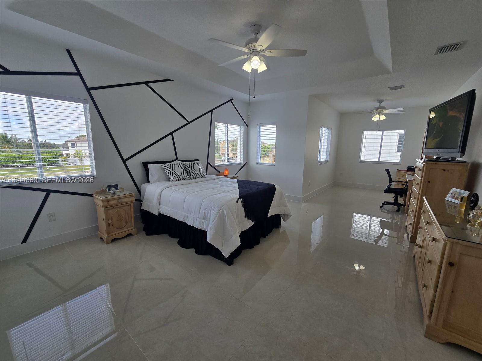 1680 Southwest 154th Path Miami, FL 33185 - Photo 78 of 100 a spacious bedroom with a bed a chandelier and a flat screen tv