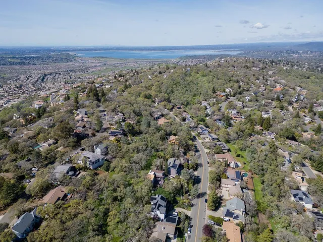 an aerial view of a house with a yard and mountain view in back