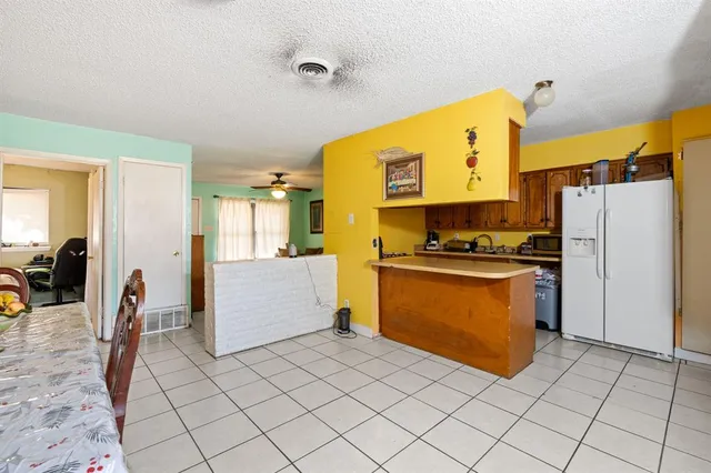 a kitchen with a refrigerator a stove top oven and a view of living room