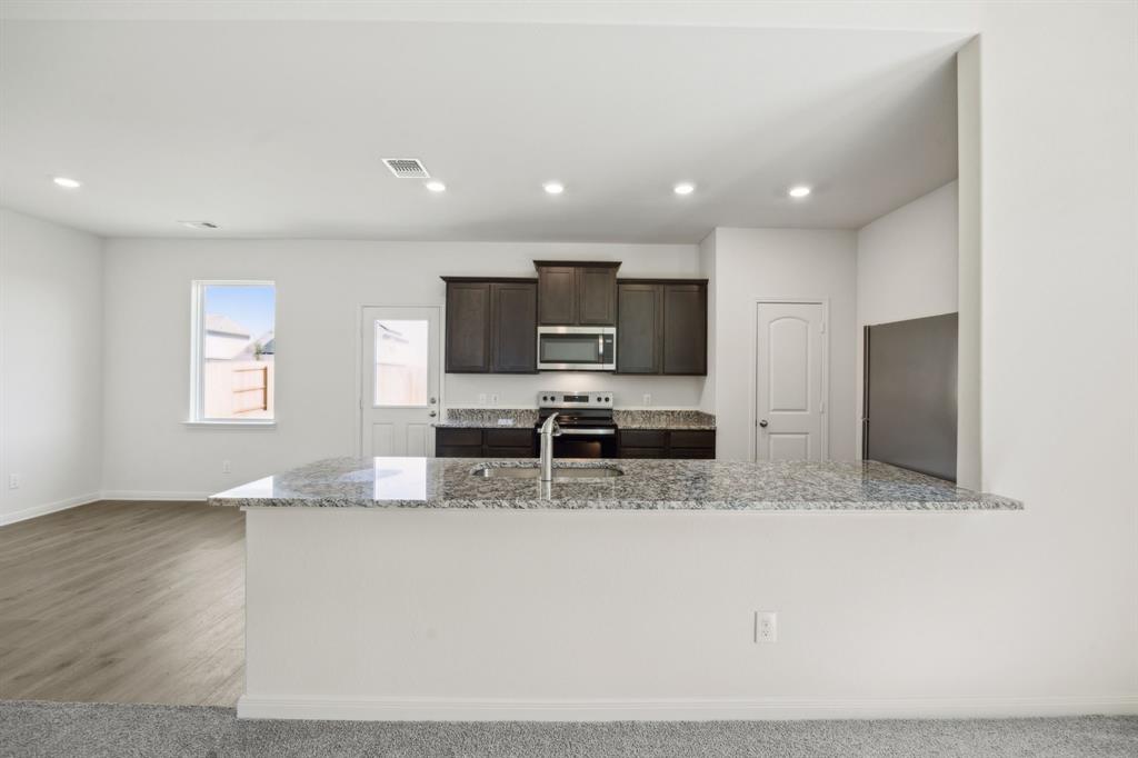 9908 Fighting Falcon Way Fort Worth, TX 76131 - Photo 12 of 22 a kitchen with stainless steel appliances granite countertop a sink a stove and a refrigerator