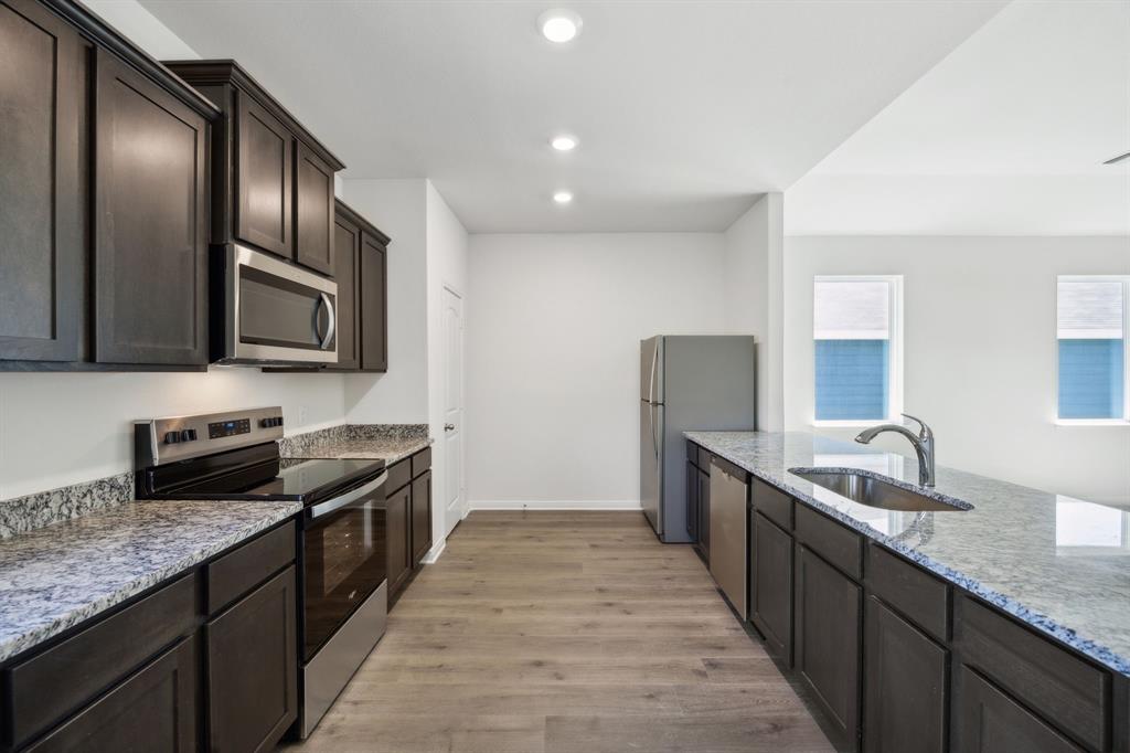 9908 Fighting Falcon Way Fort Worth, TX 76131 - Photo 13 of 22 a kitchen with granite countertop stainless steel appliances a sink dishwasher stove top oven and wooden cabinets