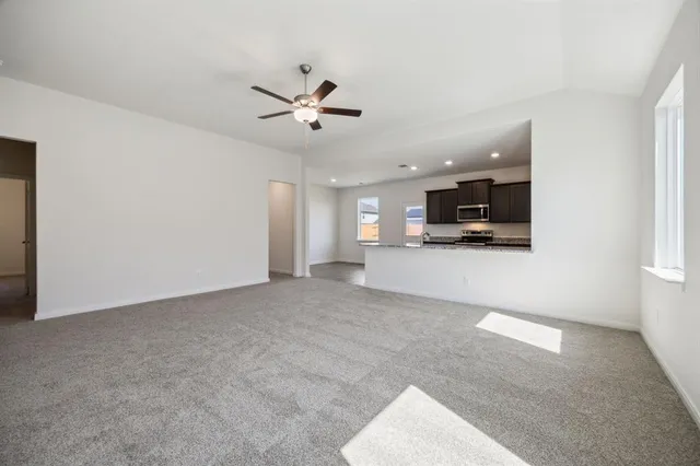 a view of a livingroom with kitchen furniture and a ceiling fan