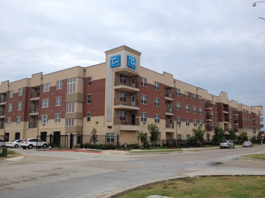 a front view of a building with lot of cars and trees