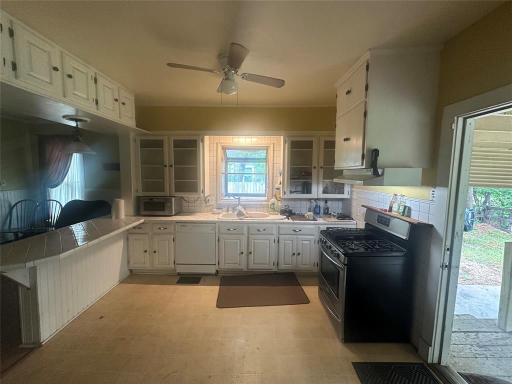 504 1st Street Terrell, TX 75160 - Photo 3 of 27 Kitchen featuring white cabinetry, a tile backsplash, and a ceiling fan with integrated lighting