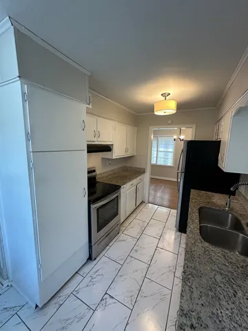 a kitchen with granite countertop a refrigerator and a stove top oven
