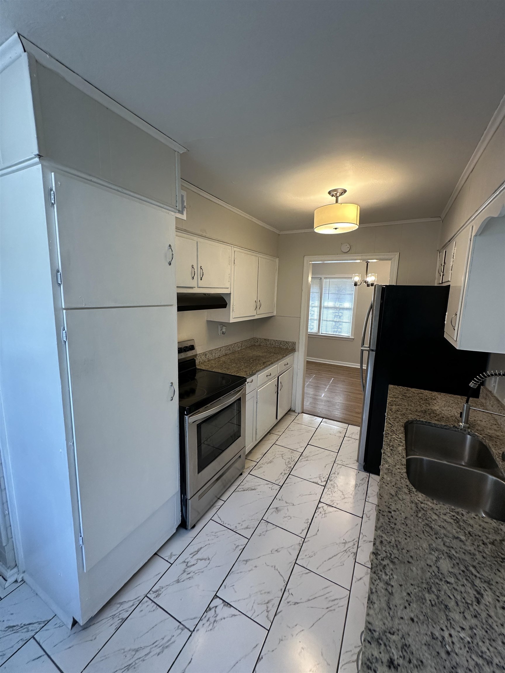 470 Dreger Road Memphis, TN 38109 - Photo 6 of 19 Kitchen with stainless steel appliances, light marble finish flooring, white cabinets, crown molding, and dark stone counters
