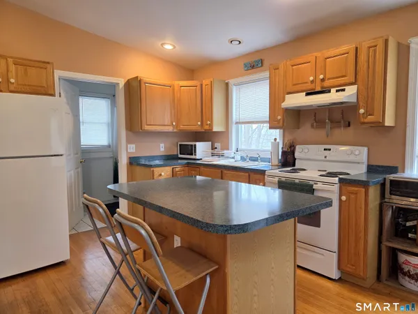 a kitchen with kitchen island granite countertop a sink a stove and a refrigerator