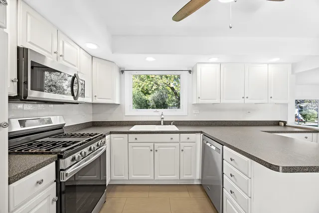 a kitchen with granite countertop a sink a stove a microwave and cabinets
