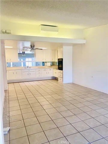a view of kitchen and empty room with wooden floor