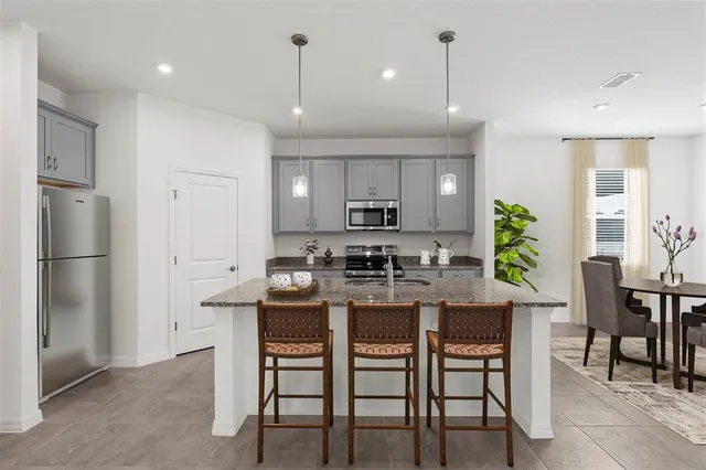 a kitchen with kitchen island a dining table chairs stainless steel appliances and cabinets