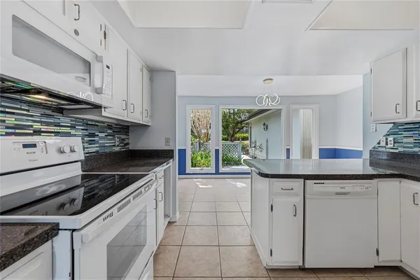 a kitchen with granite countertop white cabinets and appliances