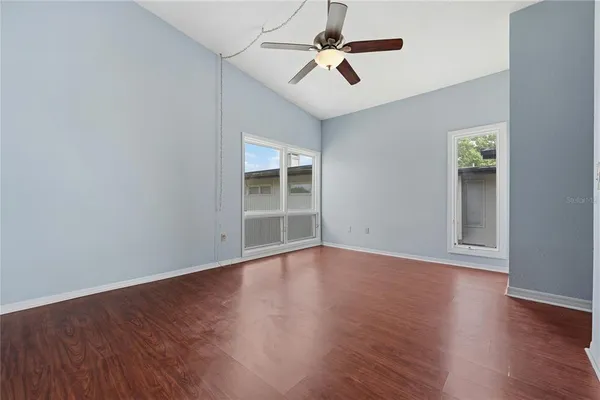 a view of empty room with wooden floor and ceiling fan