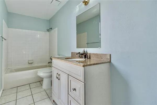 a bathroom with a granite countertop sink a toilet a mirror a bathtub and shower