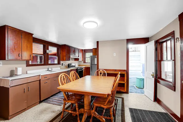 a open kitchen with stainless steel appliances granite countertop a refrigerator a sink dishwasher a dining table and chairs with wooden floor