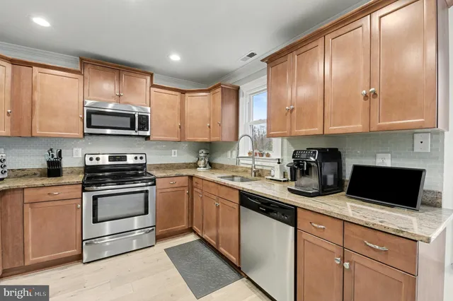 a kitchen with stainless steel appliances granite countertop a refrigerator a stove and a sink