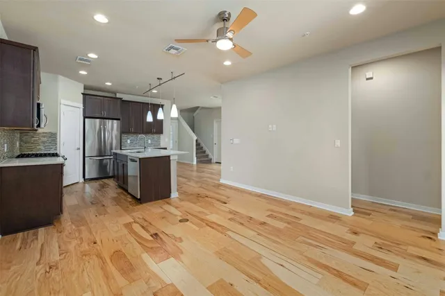 a kitchen with stainless steel appliances kitchen island granite countertop a refrigerator and a sink
