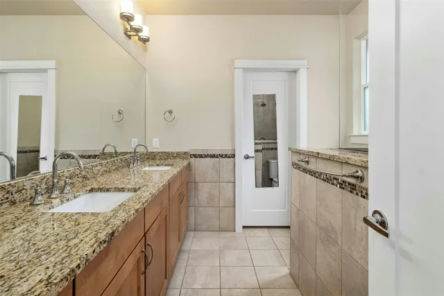 a bathroom with a granite countertop sink a mirror and a shower