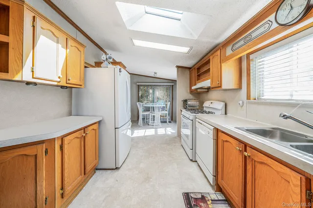 a kitchen with stainless steel appliances granite countertop a refrigerator a sink dishwasher a stove and white countertops with wooden floor