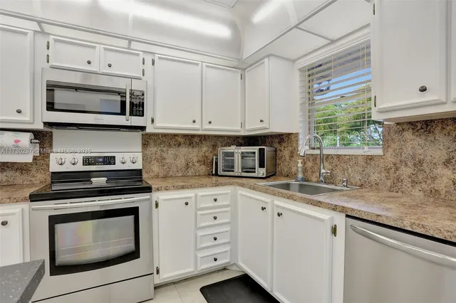 a kitchen with white cabinets appliances and a sink