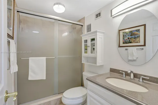 a bathroom with a granite countertop sink mirror vanity and toilet
