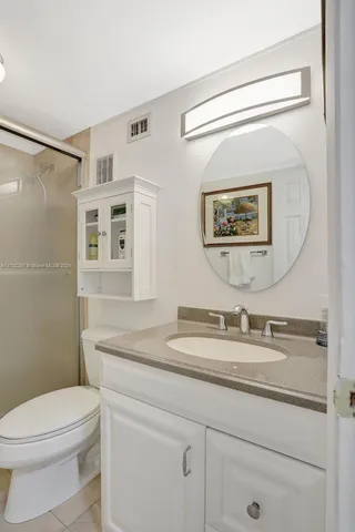 a bathroom with a granite countertop sink mirror vanity and toilet