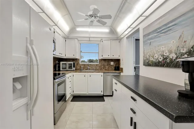 a kitchen with granite countertop a sink stainless steel appliances and white cabinets