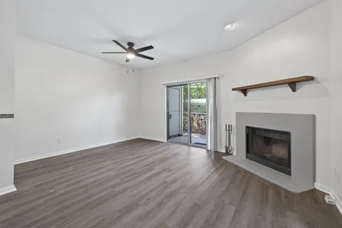 an empty room with wooden floor a fireplace and windows