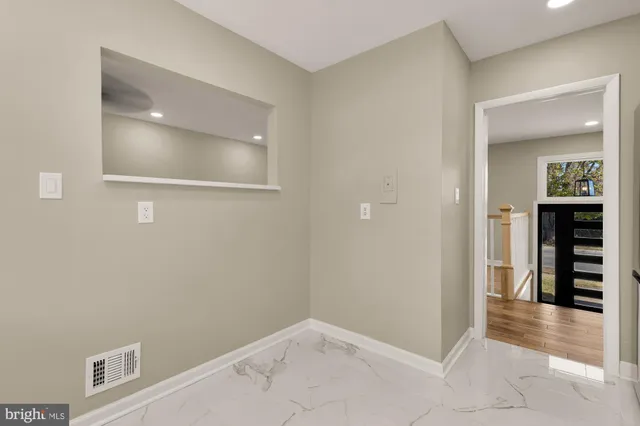 a view of a hallway with wooden floor and a bathroom