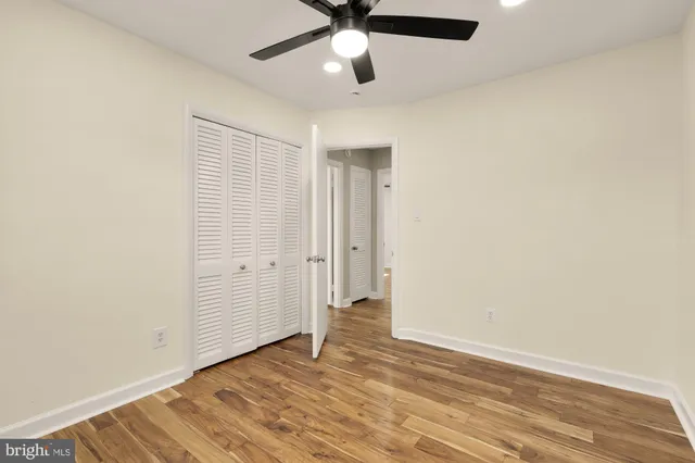 an empty room with wooden floor ceiling fan and windows