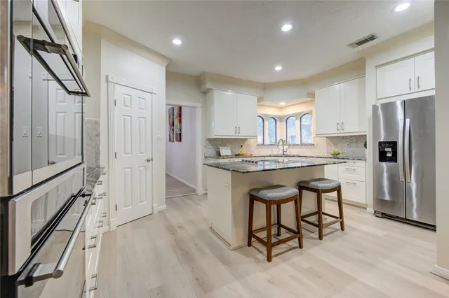 a kitchen with granite countertop a stove a sink and chairs