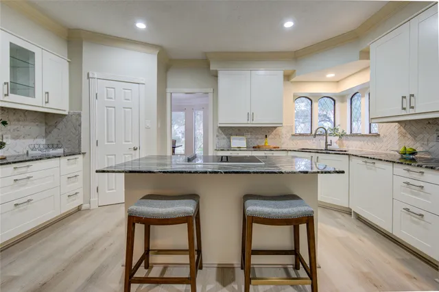 a kitchen with granite countertop white cabinets and stainless steel appliances