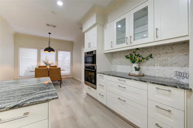 a kitchen with granite countertop cabinets a sink dishwasher a dining table and chairs with wooden floor