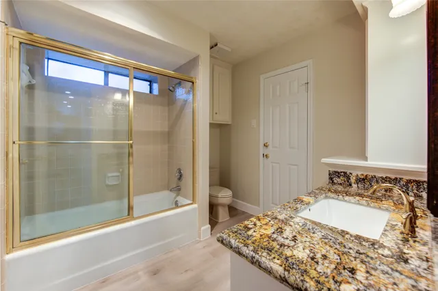 an empty room with wooden floor ceiling fan and windows