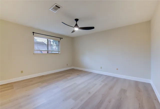 a view of empty room with wooden floor and ceiling fan