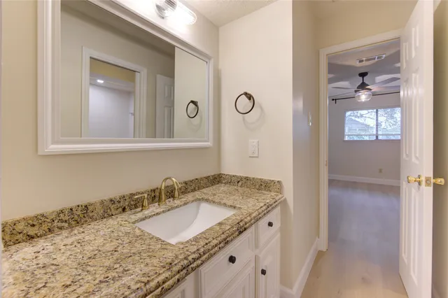 a bathroom with a granite countertop sink and a mirror