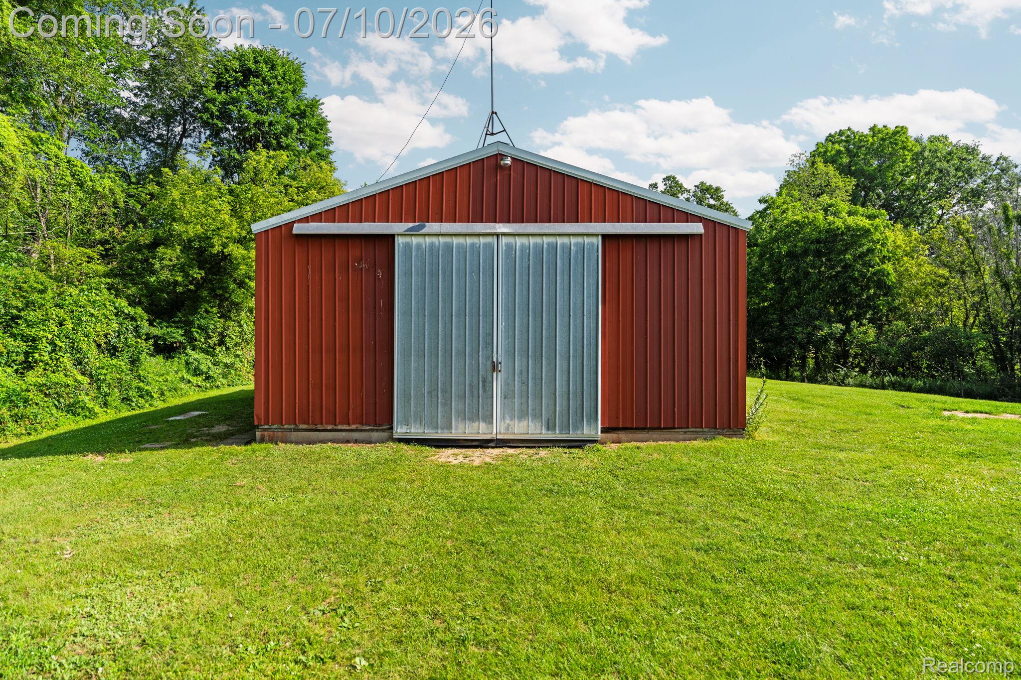 3144 North Nicholson Road Fowlerville, MI 48836 - Photo 28 of 70 Red metal-sided barn with a gabled roof and corrugated metal sliding doors
