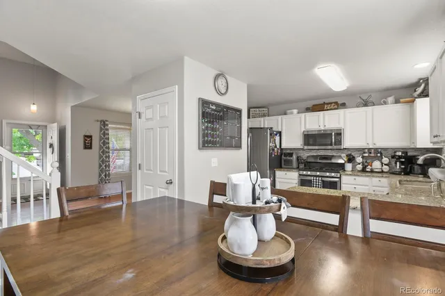 a living room with stainless steel appliances furniture and wooden floor