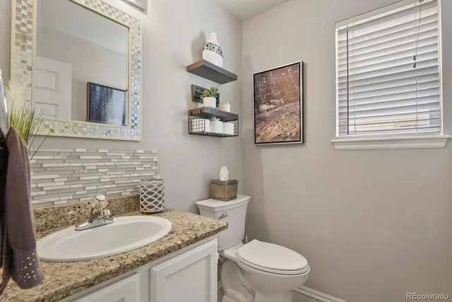a bathroom with a granite countertop toilet a sink and a mirror