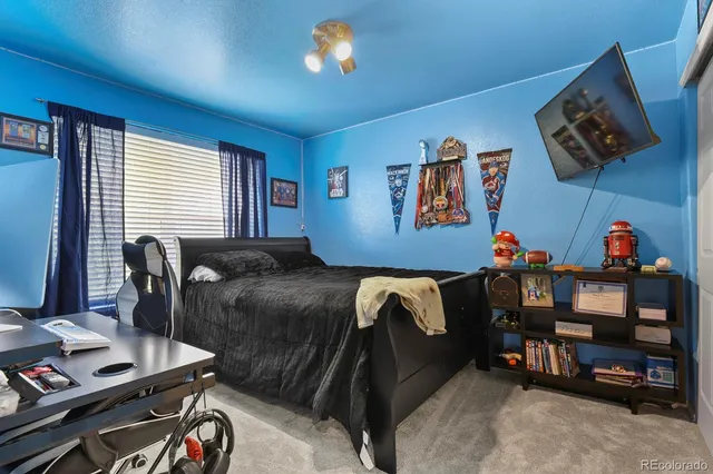 a living room with a couch and a computer on a desk next to a window