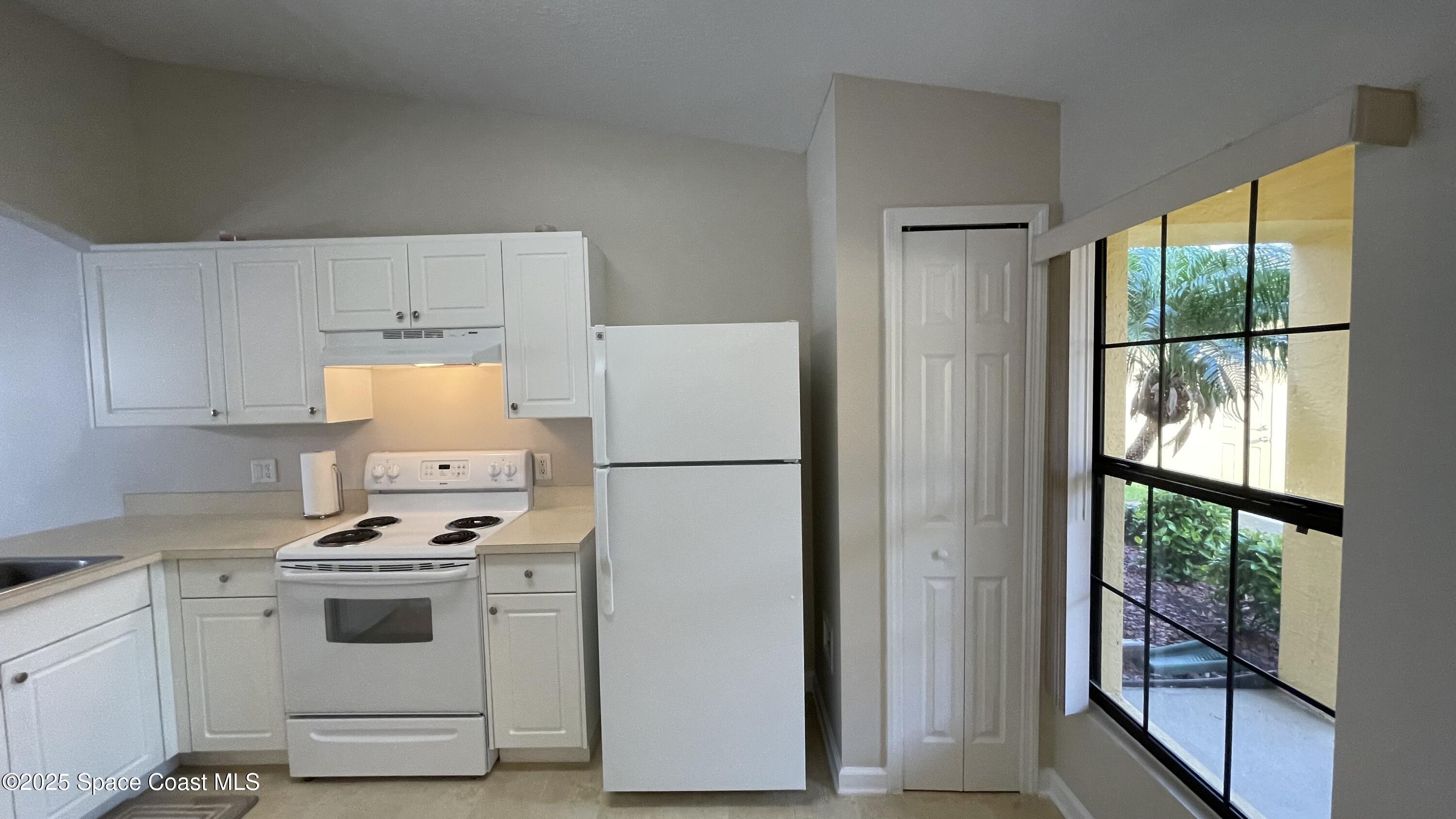 975 Luminary Circle, Unit 103 Melbourne, FL 32901 - Photo 21 of 70 a white refrigerator freezer and a stove sitting inside of a kitchen