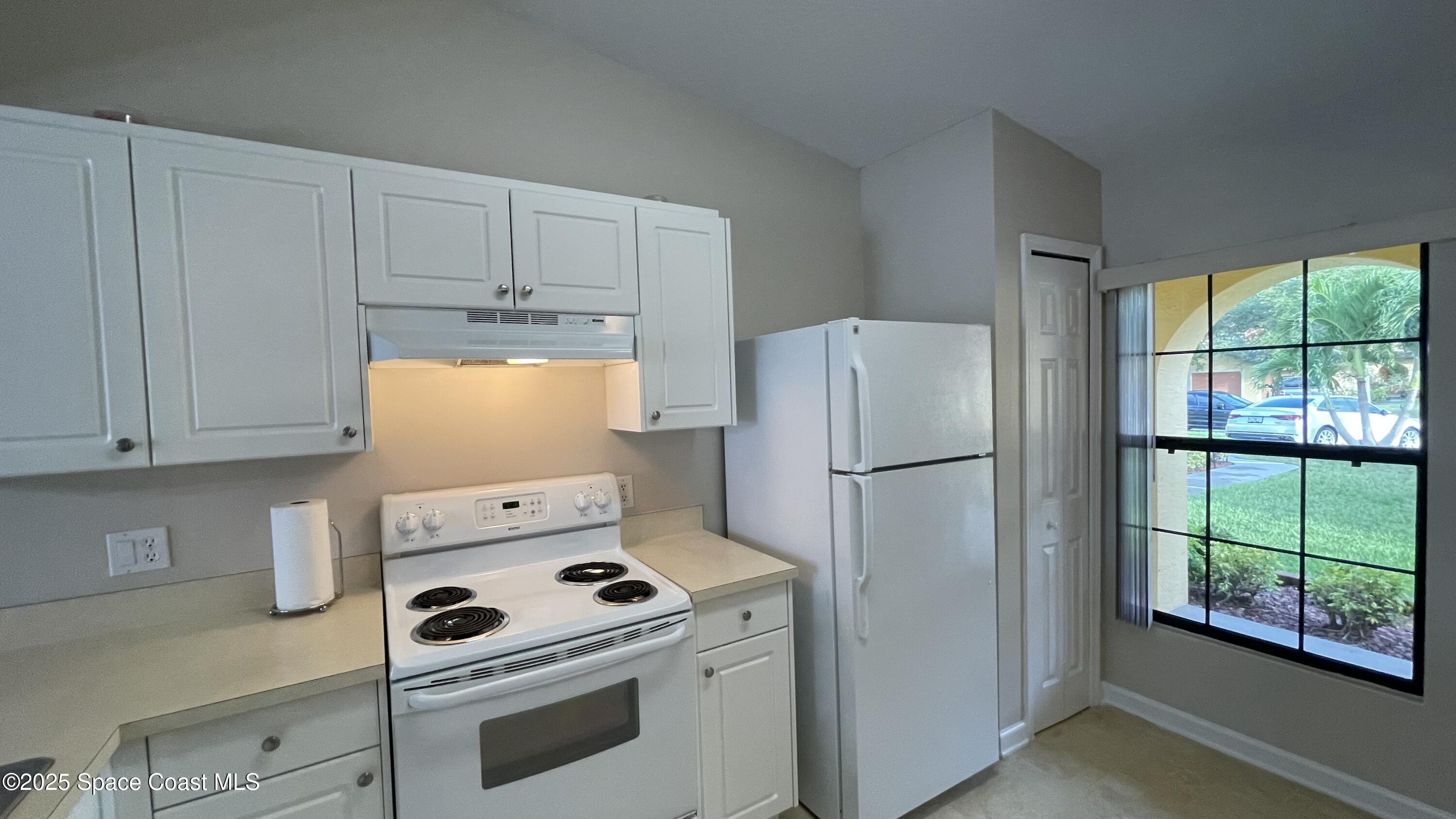 975 Luminary Circle, Unit 103 Melbourne, FL 32901 - Photo 22 of 70 a white refrigerator freezer and a stove sitting inside of a kitchen