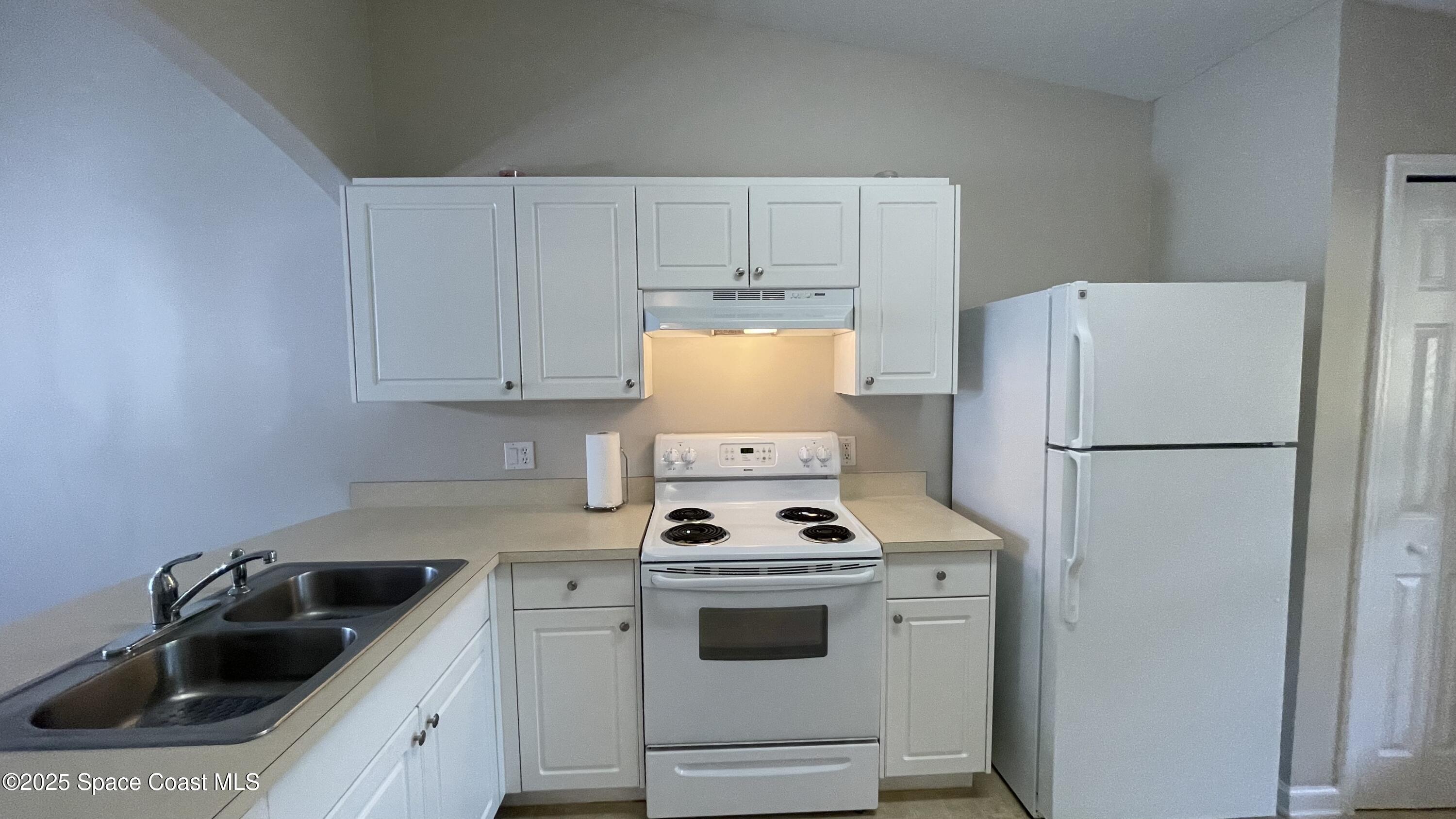 975 Luminary Circle, Unit 103 Melbourne, FL 32901 - Photo 23 of 70 a kitchen with white cabinets and white appliances