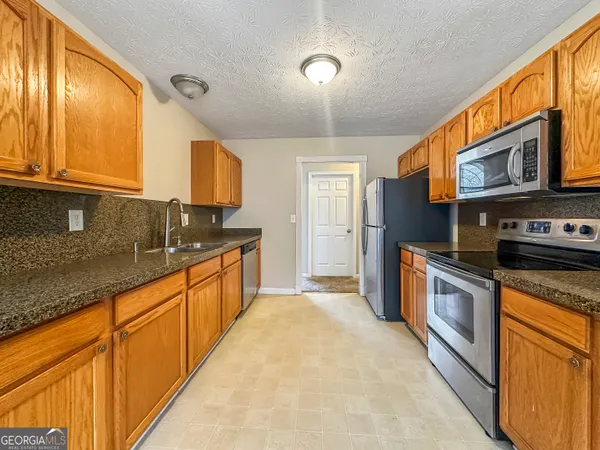 a large kitchen with stainless steel appliances granite countertop a stove a sink and a microwave